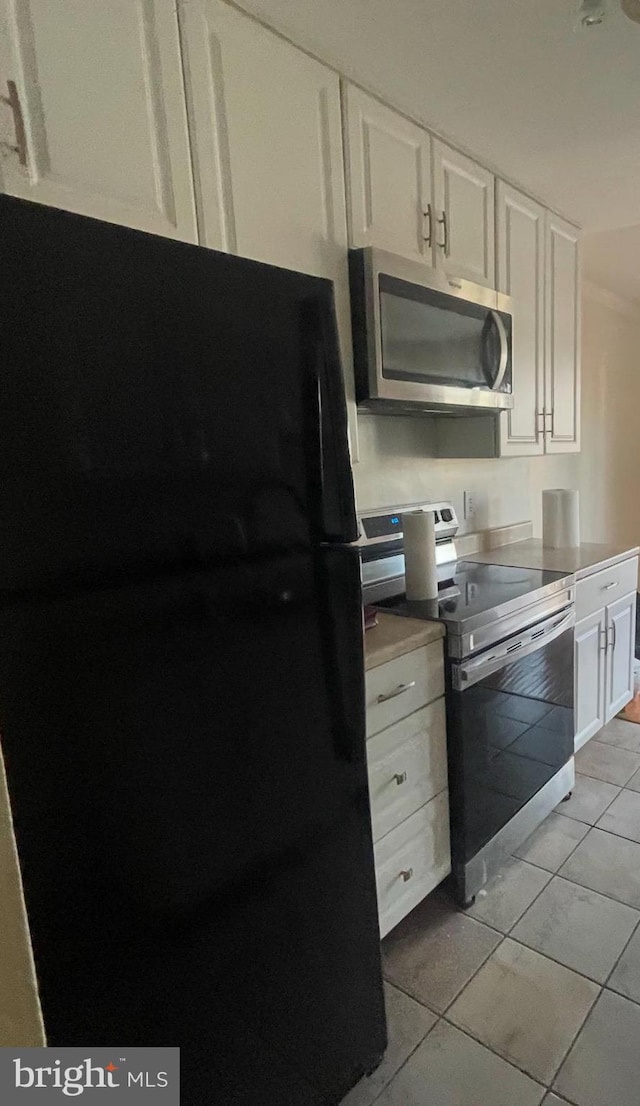 kitchen featuring appliances with stainless steel finishes, white cabinetry, and light tile patterned floors