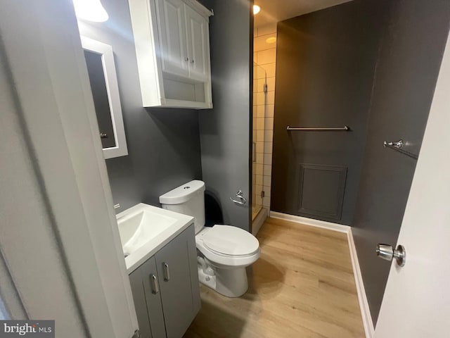 bathroom with toilet, vanity, wood-type flooring, and a shower