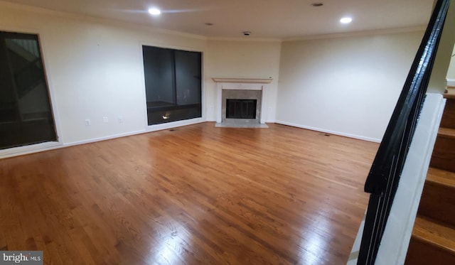 unfurnished living room with wood-type flooring, crown molding, and a high end fireplace