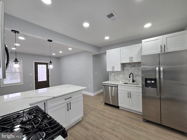 kitchen with sink, white cabinetry, hanging light fixtures, stainless steel appliances, and light stone countertops