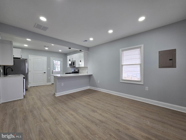 kitchen featuring decorative light fixtures, stainless steel appliances, kitchen peninsula, and white cabinets