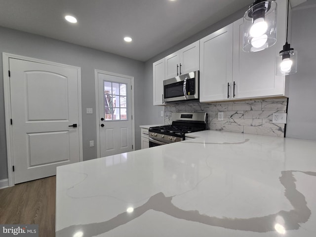 kitchen featuring appliances with stainless steel finishes, light stone countertops, decorative backsplash, and white cabinets