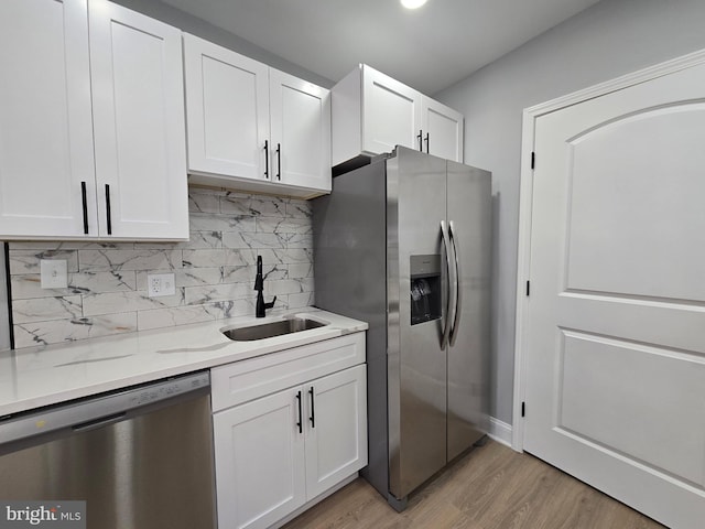 kitchen featuring white cabinetry, sink, stainless steel appliances, and light stone countertops