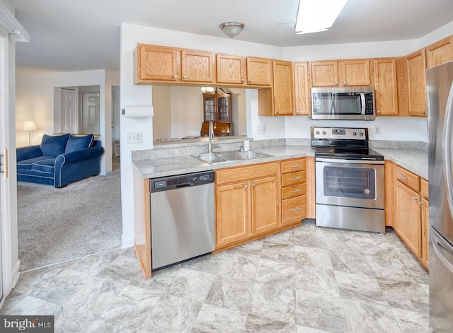 kitchen with open floor plan, light countertops, appliances with stainless steel finishes, and a sink