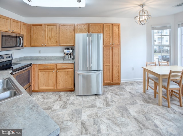 kitchen featuring visible vents, decorative light fixtures, stainless steel appliances, light countertops, and a sink