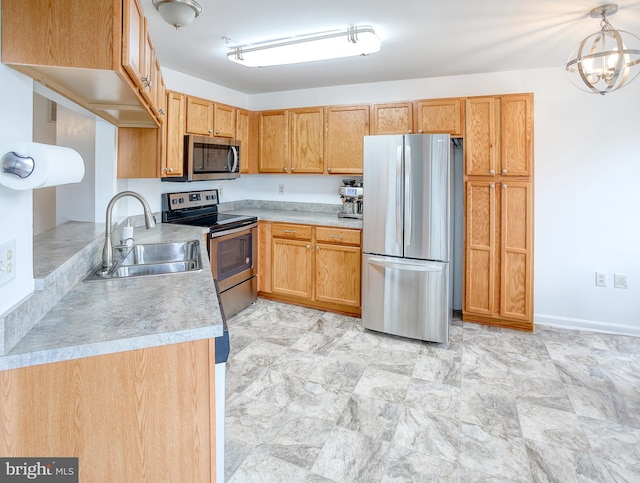 kitchen featuring light countertops, hanging light fixtures, appliances with stainless steel finishes, a sink, and a chandelier