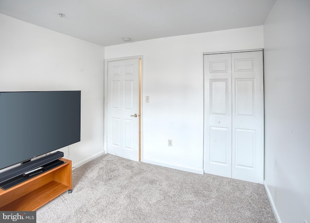 unfurnished bedroom featuring light carpet, baseboards, and a closet