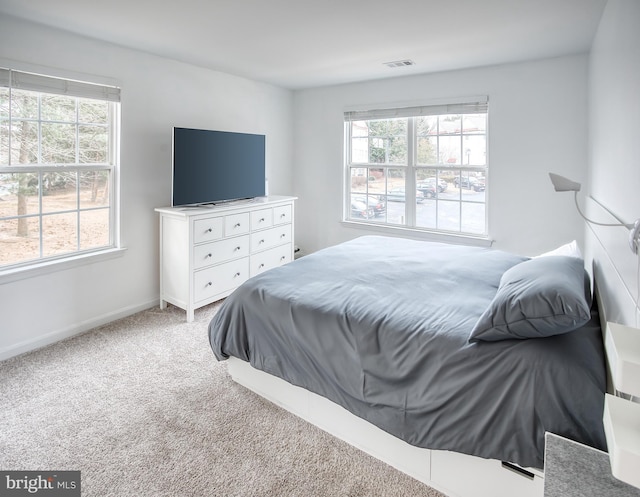 bedroom with light carpet, baseboards, multiple windows, and visible vents