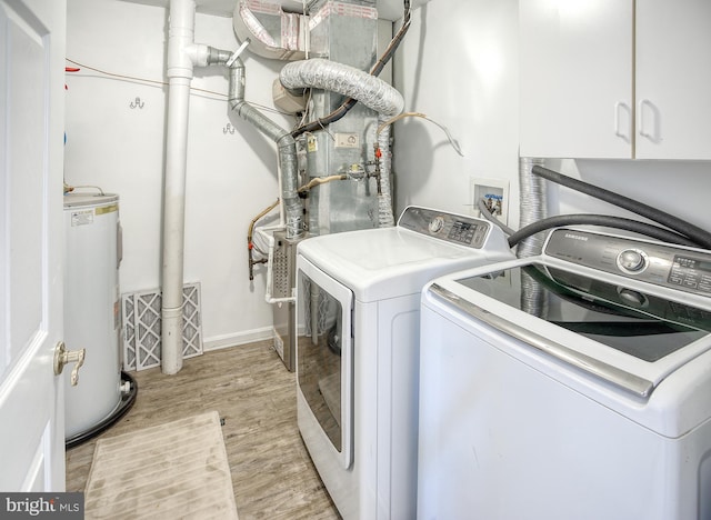 laundry room featuring water heater, light wood finished floors, cabinet space, and washer and dryer