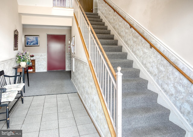 stairway featuring a wainscoted wall, carpet, and a towering ceiling