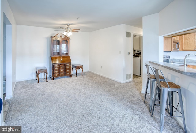 interior space with washer / dryer, light colored carpet, visible vents, and a ceiling fan