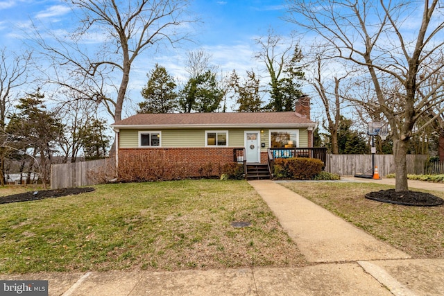 view of front of property featuring brick siding, fence, a chimney, and a front lawn