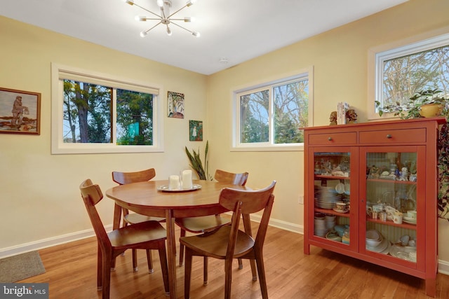 dining area featuring light wood finished floors, baseboards, and an inviting chandelier