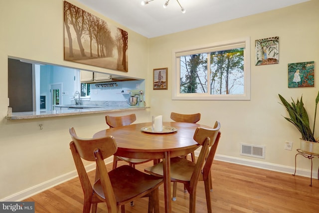 dining room featuring light wood-type flooring, baseboards, and visible vents