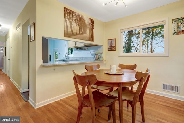 dining room featuring baseboards, visible vents, and light wood finished floors