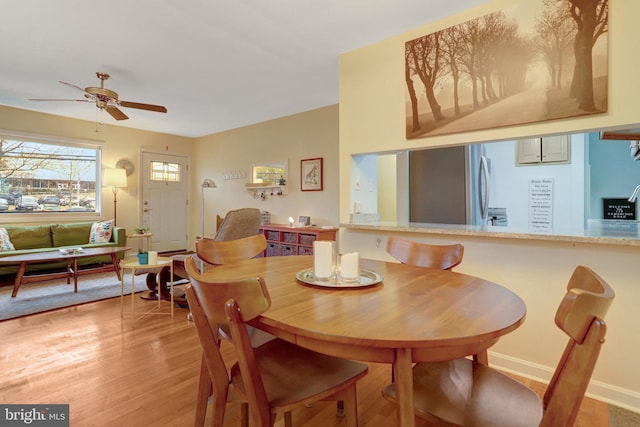 dining room with a ceiling fan, light wood-style flooring, and baseboards