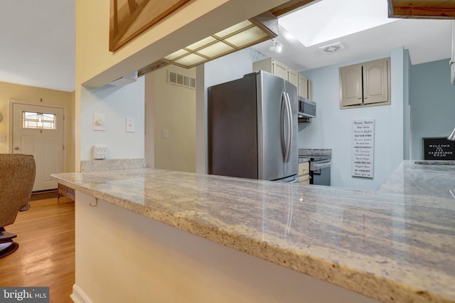 kitchen with a peninsula, a skylight, visible vents, light wood-style floors, and appliances with stainless steel finishes