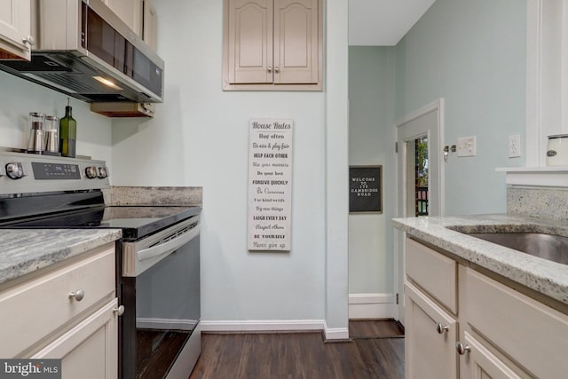 kitchen featuring stainless steel appliances, light stone counters, dark wood-style flooring, and baseboards