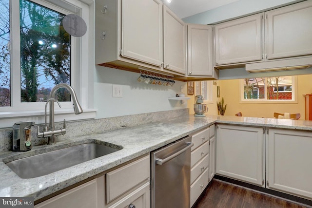 kitchen with dark wood-type flooring, light stone countertops, stainless steel dishwasher, white cabinetry, and a sink