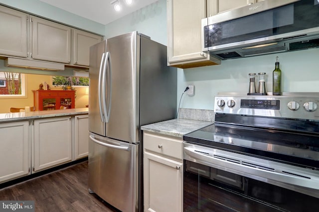 kitchen with appliances with stainless steel finishes, dark wood-type flooring, and light stone counters