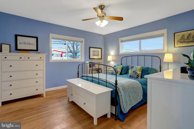 bedroom featuring light wood-style floors, multiple windows, ceiling fan, and baseboards