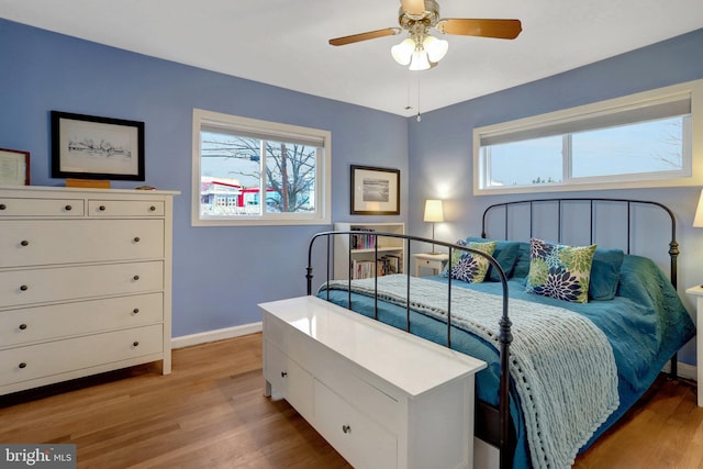 bedroom with multiple windows, light wood-type flooring, and baseboards