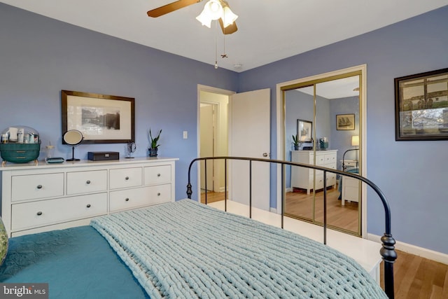 bedroom featuring a ceiling fan, a closet, baseboards, and wood finished floors