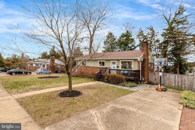 view of front of property with a chimney, a front yard, fence, and a wooden deck