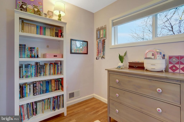 living area with light wood-style flooring, visible vents, and baseboards