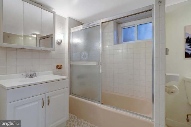 full bathroom featuring toilet, bath / shower combo with glass door, vanity, tile walls, and backsplash