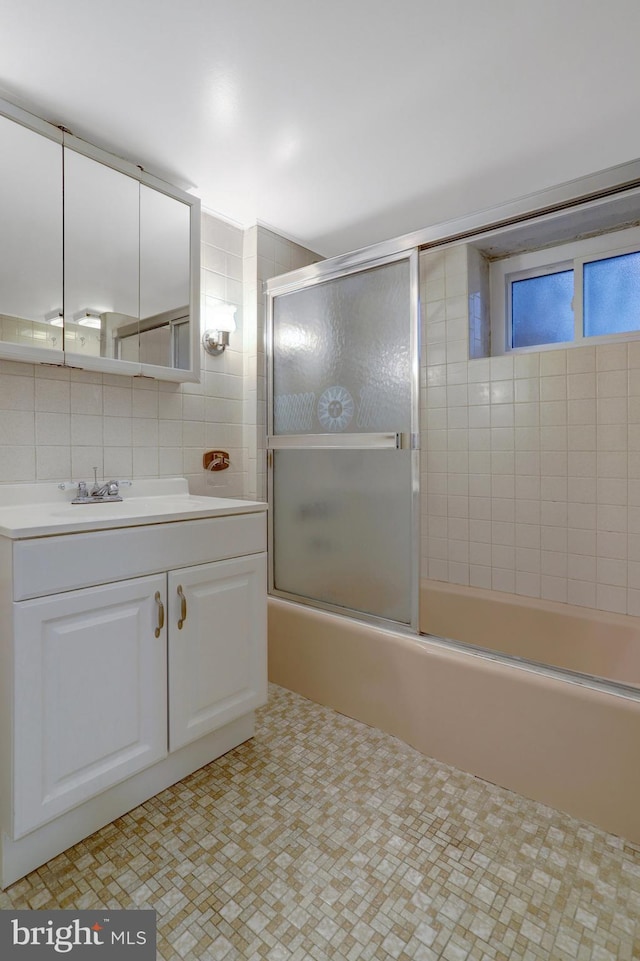 bathroom featuring combined bath / shower with glass door, vanity, tile walls, and tasteful backsplash