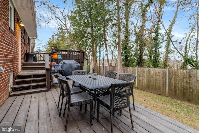 wooden deck featuring outdoor dining space, a fenced backyard, and grilling area