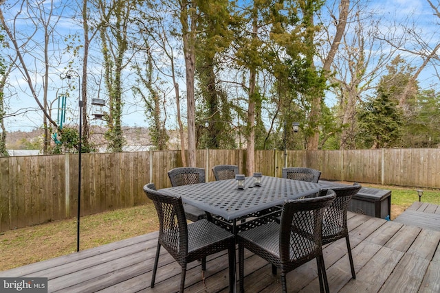 wooden terrace with a fenced backyard and outdoor dining area