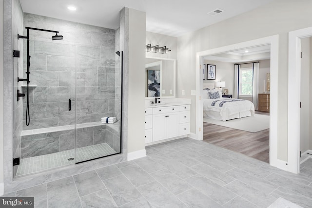 bathroom featuring a raised ceiling, vanity, and a shower with shower door