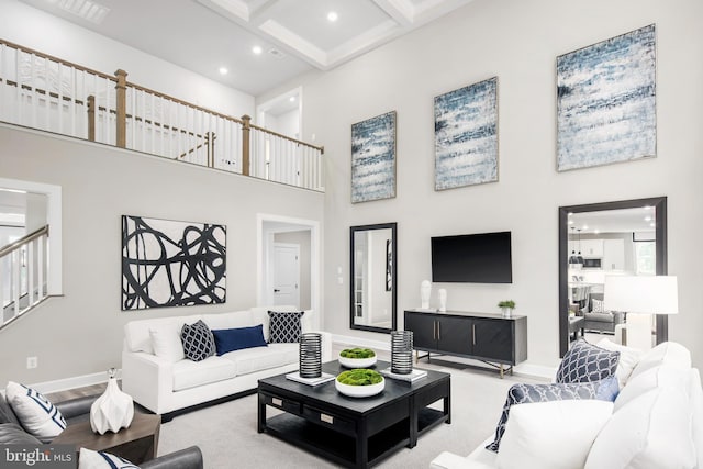 living room with beamed ceiling, a towering ceiling, coffered ceiling, and light hardwood / wood-style floors