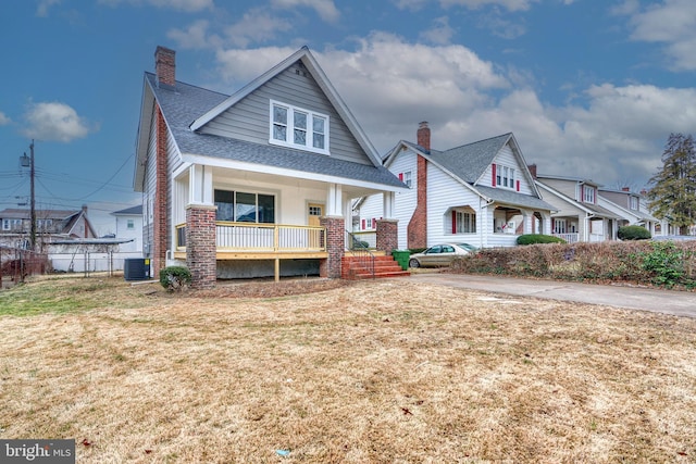 view of front of home featuring a porch, a front lawn, and central air condition unit