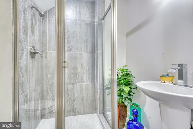 bathroom featuring toilet, sink, and a shower with door