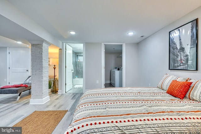 bedroom with connected bathroom, light hardwood / wood-style flooring, washer / clothes dryer, and ornate columns