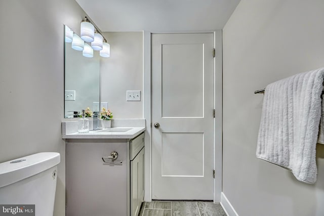 bathroom with hardwood / wood-style flooring, vanity, and toilet