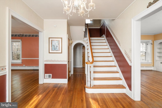 stairway with a wealth of natural light, a baseboard radiator, and wood-type flooring