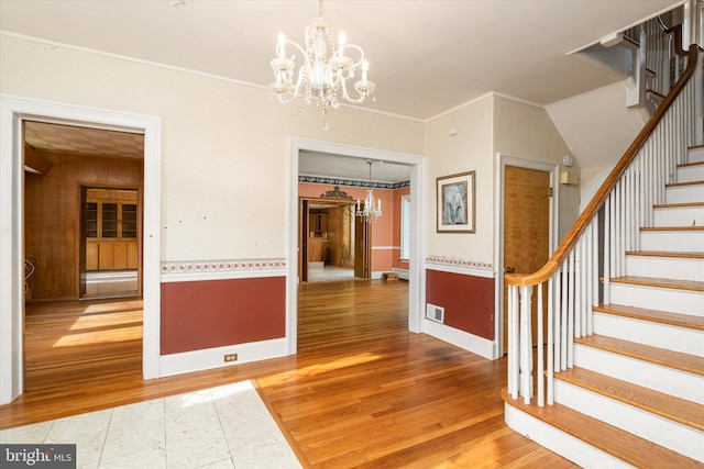 unfurnished dining area with hardwood / wood-style flooring, crown molding, and a notable chandelier