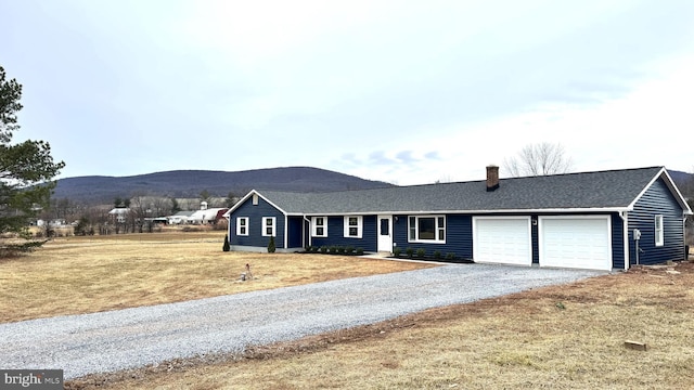 ranch-style home with a mountain view, a garage, and a front lawn