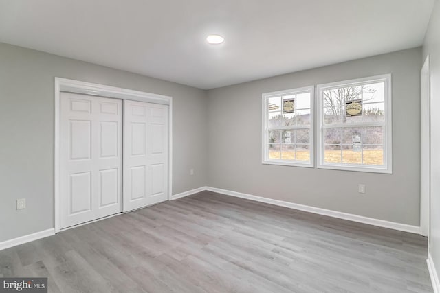 unfurnished bedroom with light hardwood / wood-style flooring and a closet