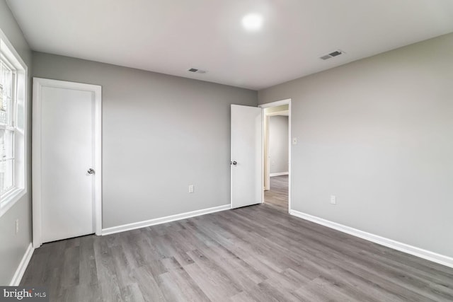 unfurnished bedroom with light hardwood / wood-style floors and multiple windows