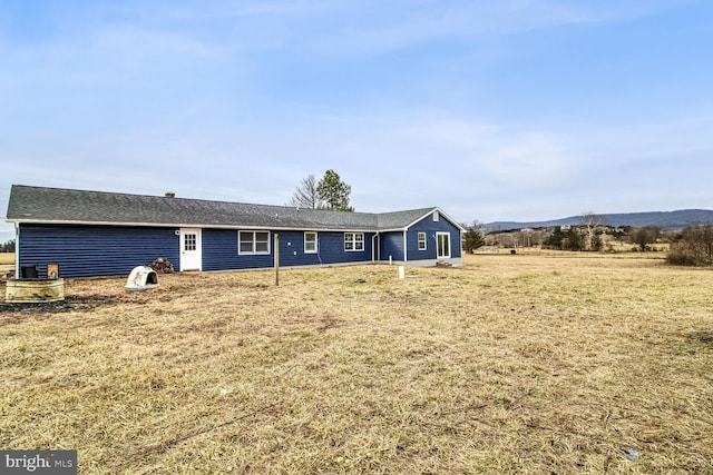 back of property featuring a mountain view and a lawn