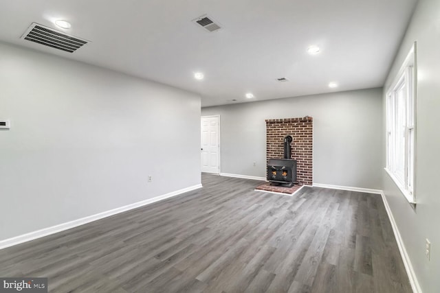 unfurnished living room with dark wood-type flooring and a wood stove