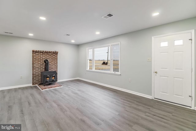 unfurnished living room with wood-type flooring and a wood stove