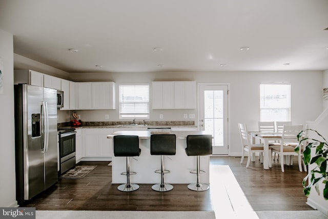 kitchen featuring appliances with stainless steel finishes, white cabinetry, sink, a kitchen breakfast bar, and a center island