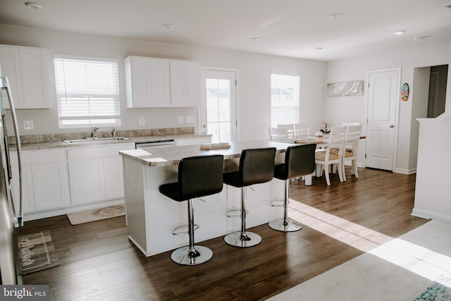 kitchen with sink, plenty of natural light, dark hardwood / wood-style floors, a center island, and white cabinets