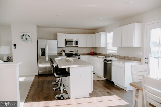 kitchen featuring sink, a breakfast bar, white cabinetry, stainless steel appliances, and a center island